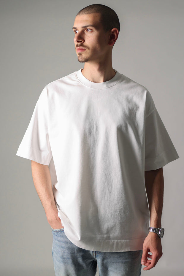 Man wearing a plain white t-shirt against a gray background